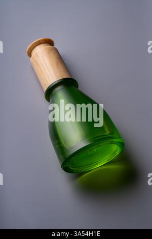 Matte glass green dropper bottle with bamboo lid on solid gray background. Skin care cosmetics mockup. natural essential oil and skin care products Stock Photo