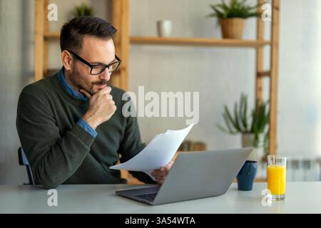Business man accountant analyst holding documents, work at laptop computer doing online trade market Stock Photo
