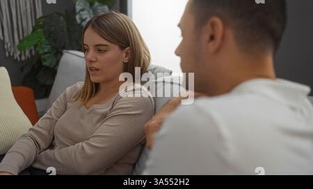 Woman and man in casual clothing sitting together talking in a cozy living room interior, conveying a sense of relationship and companionship in a mod Stock Photo