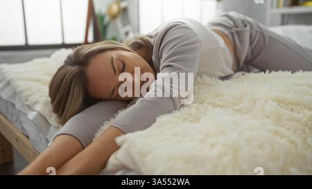 Woman relaxing on a cozy bed in a sunlit bedroom, embodying tranquility and peacefulness in a serene home setting, surrounded by soft, inviting textur Stock Photo