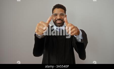 Young man in graduation attire giving thumbs up over isolated white background Stock Photo