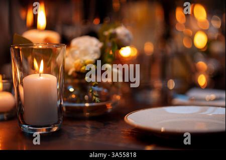 Candle close up at the wooden table with setting plates Stock Photo