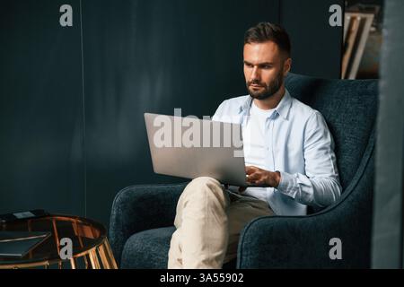Focused, confident. Businessman is sitting and working by using laptop. Stock Photo