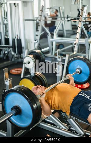 Athletic man powerfully doing bench press in gym Stock Photo
