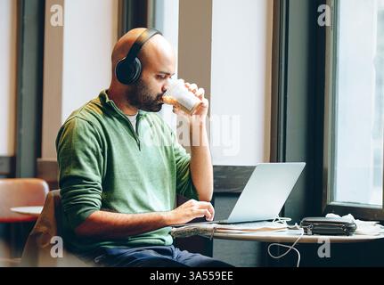 A man using a laptop by the window Stock Photo