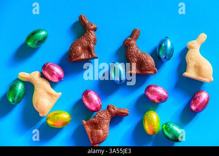 Easter chocolate eggs in foil and Easter chocolate bunnies on blue background. Top view Stock Photo