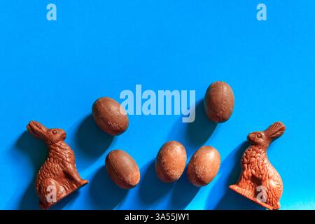 Easter chocolate bunnies and chocolate eggs on blue background. Top view Stock Photo