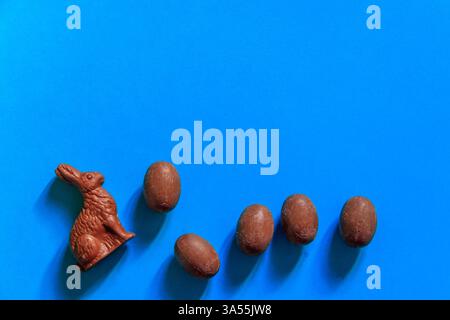 Easter chocolate bunnies and chocolate eggs on blue background. Top view Stock Photo