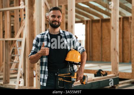Job is going fine, showing thumb up. Industrial worker in wooden warehouse. Stock Photo
