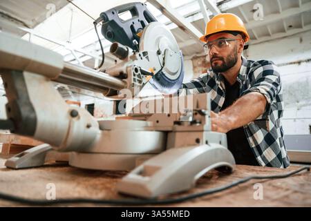 Focused, woodworking. Man is in warehouse. Stock Photo