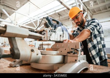 Focused, woodworking. Man is in warehouse. Stock Photo
