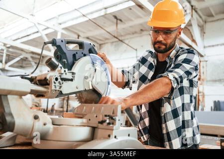 Focused, woodworking. Man is in warehouse. Stock Photo