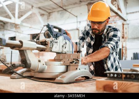 Focused, woodworking. Man is in warehouse. Stock Photo
