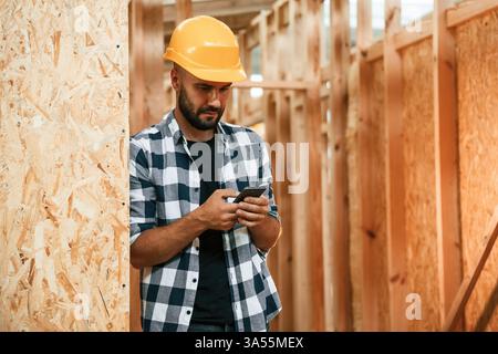 Using the smartphone. Industrial worker in wooden warehouse. Stock Photo