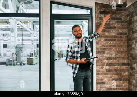 Showing the wooden house that is under construction. Industrial worker in warehouse. Stock Photo