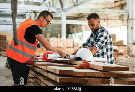 Having a deal, handshake. Two workers are in the industrial wooden warehouse. Stock Photo