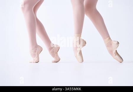 Close-up of ballet dancers' feet in pointe shoes, performing graceful movements on a white background. Aesthetic dance and elegance Stock Photo