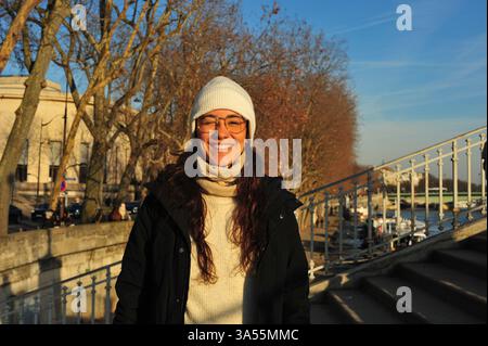 Beautiful woman smiling and blinking because of the sun in her face in Paris Streets Stock Photo