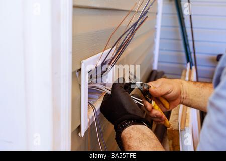 An electrician carefully strips wires while installing electrical connections during home renovation working Stock Photo