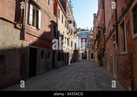 A small calle in Venice winds between historic buildings, leading to a quiet canal. High quality photo Stock Photo