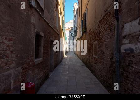A small calle in Venice winds between historic buildings, leading to a quiet canal. High quality photo Stock Photo