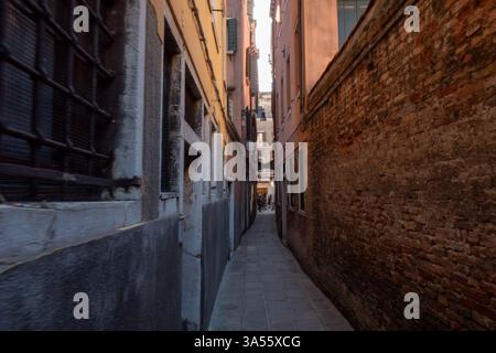 A small calle in Venice winds between historic buildings, leading to a quiet canal. High quality photo Stock Photo