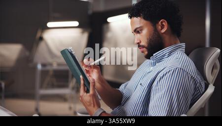Businessman, graphic designer or writing with tablet for project development or digital layout at office. Man, engineer or working late with Stock Photo