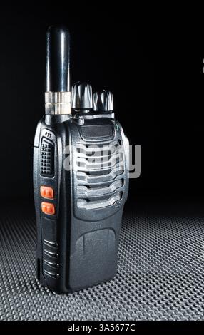 Walkie talkie for communicating in an emergency with a short aerial on rubber work mat with a black background. Stock Photo