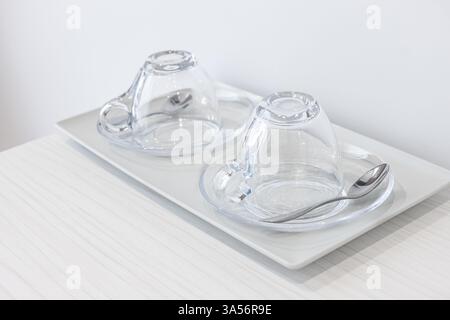 Transparent tea glasses for tea and drinks on a table, close up. Two empty clear tea cups upside down on a tray. Empty clear tea glass cup saucer arra Stock Photo