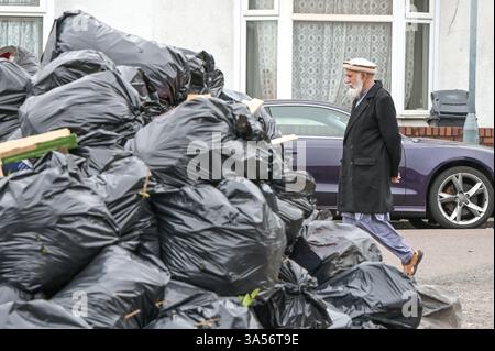 Shakespeare Street, Birmingham 21st March 2025: A man walks past a huge mountain of rubbish and bin bags on Shakespeare Street in the Sparkhill area of Birmingham as council refuse workers continue to strike on every working day until their demands are met. Talks on Thursday evening between the council and Unite failed to resolve issues. Residents have complained that one mountain of waste has been festering for several weeks outside their homes. More than 350 refuse workers began industrial action in January over the scrapping of the safety critical Waste Recycling and Collection Officer (WRC Stock Photo