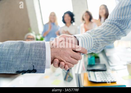 Business professionals shaking hands in an office, symbolizing partnership and teamwork Stock Photo