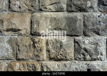 Fragment of an old wall of rough stone blocks in gray for use as abstract backgrounds and textures. Stock Photo