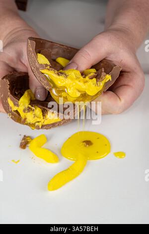 Confectioner showing chocolate Easter egg with banana syrup filling vertical. Stock Photo