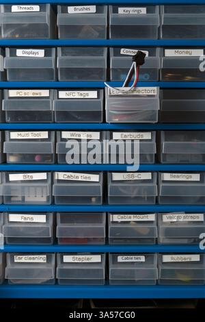 A blue shelf with many clear plastic containers labeled with various items. The containers are organized and labeled, making it easy to find what you Stock Photo