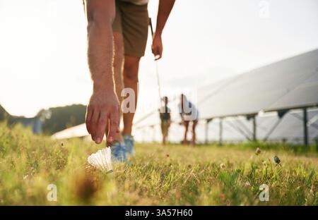 Tranquil, playing badminton. Father, mother and little son are outdoors near solar panels. Stock Photo