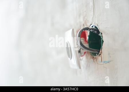 An unfinished electrical outlet with electrical wires plugged into the wall in the apartment. High quality photo Stock Photo