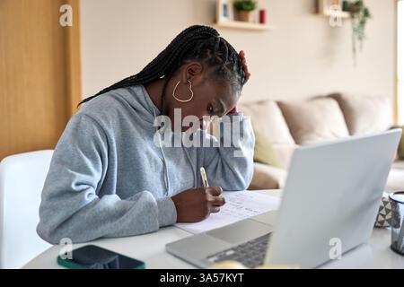 Focused black woman taking notes while studying at home Stock Photo