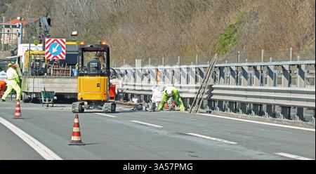 road construction site with excavator and cones to reduce lanes and workers at work in europe Stock Photo