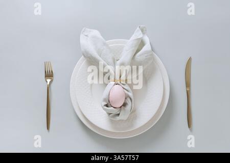Easter spring table setting with pink egg on gray background. Happy creative Easter decoration. View from above. Stock Photo