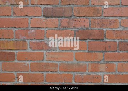 A brick wall with a few bricks missing. The wall is red and has a rough texture. The missing bricks give the wall a sense of unfinishedness and a feel Stock Photo