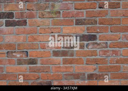 A brick wall with a few missing bricks. The wall is brown and has a rough texture. The missing bricks give the wall a somewhat unfinished look Stock Photo