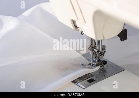 Tailoring Process on Sewing Machine with White Cloth. Macro shot of a sewing machine in action with white cloth under the needle. Stock Photo