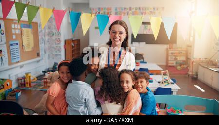 Happy, portrait and children hugging teacher in classroom for bonding, learning and thank you. Love, kids or students embracing woman educator for Stock Photo