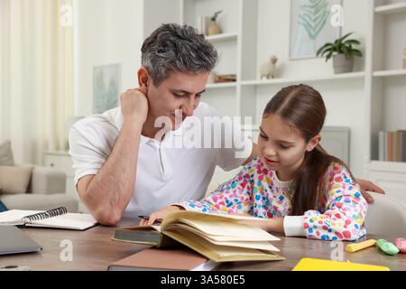 Father helping his daughter with homework at table indoors Stock Photo