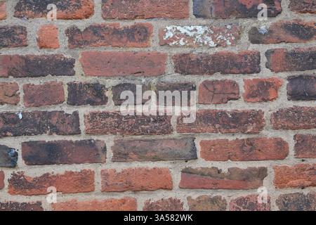 A brick wall with a few white spots. The wall is made of red bricks. The wall is old and has a rustic look Stock Photo