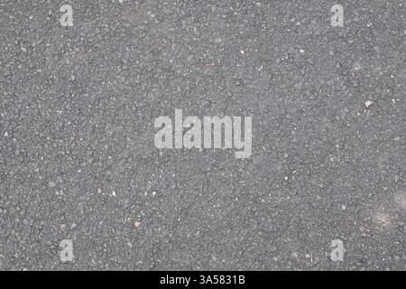 A grey and black road with gravel. The road is empty and has no cars or people on it Stock Photo