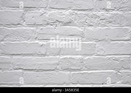 A white brick wall with a few bricks missing. The wall is very plain and simple Stock Photo