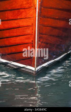 bow of wooden boat with detailed craftsmanship and calm water reflection Stock Photo