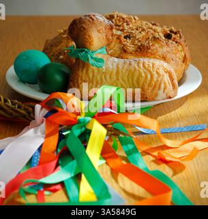 Easter still life containing a small lamb cake, painted eggs, traditional Czech Easter sweet cake called "mazanec" on white plate and an Easter whip Stock Photo