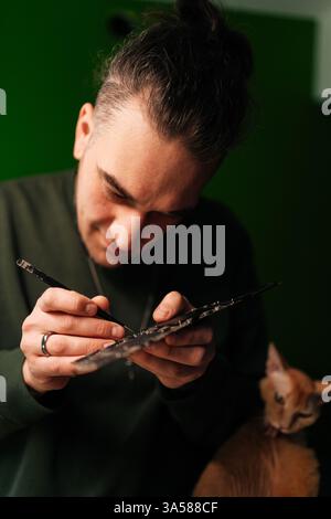 Close-up vertical portrait of focused technician cleaning delicate motherboard components with precision brush, showcasing careful hardware Stock Photo